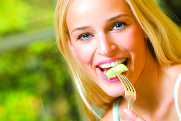 Portrait of young happy smiling woman eating salad